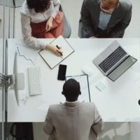 Top down shot of male and female HR professionals greeting Afro-American businessman with handshake, reading his CV and having talk during job interview in office